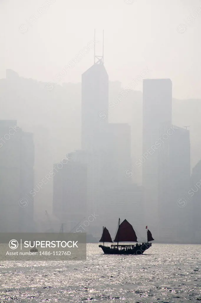 Junk boat in the sea with skyscrapers in the background, Victoria Harbor, Hong Kong, China