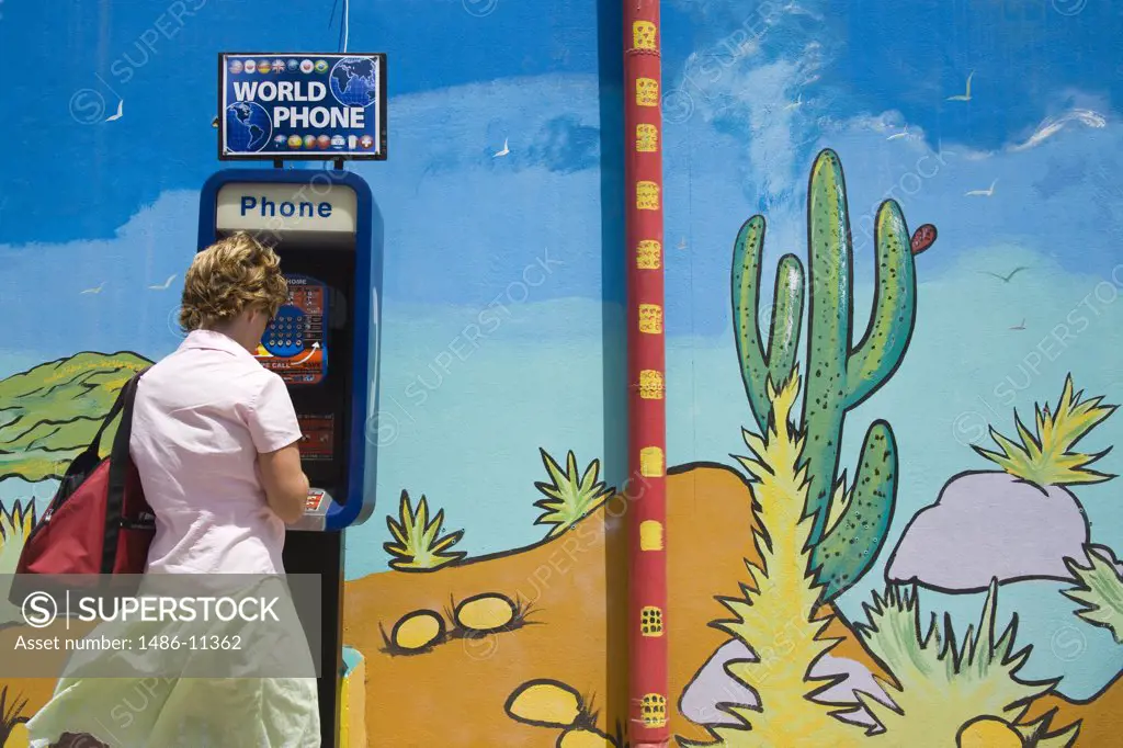 Woman using a public telephone, Oranjestad, Aruba