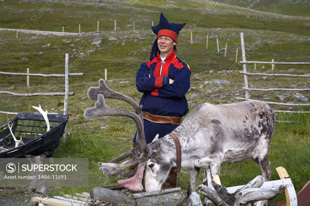 Sami tribal man standing beside a reindeer, Honningsvag, Mageroya Island, Nordkapp, Finnmark County, Norway