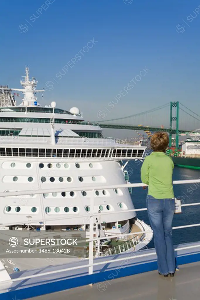 Woman watching Royal Caribbean cruise ship at the port with a bridge in the background, Vincent Thomas Bridge, San Pedro, Los Angeles, California, USA