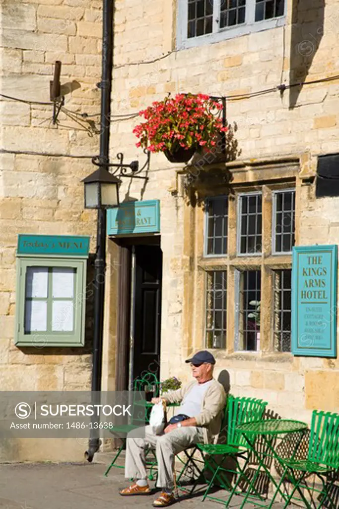 Tourist sitting at the entrance of a hotel, The Kings Arms Hotel, Stow-on-the-Wold, Gloucestershire, England