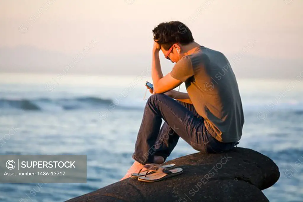 Man sitting on the beach and listening the mp3 player, La Jolla, San Diego, California, USA