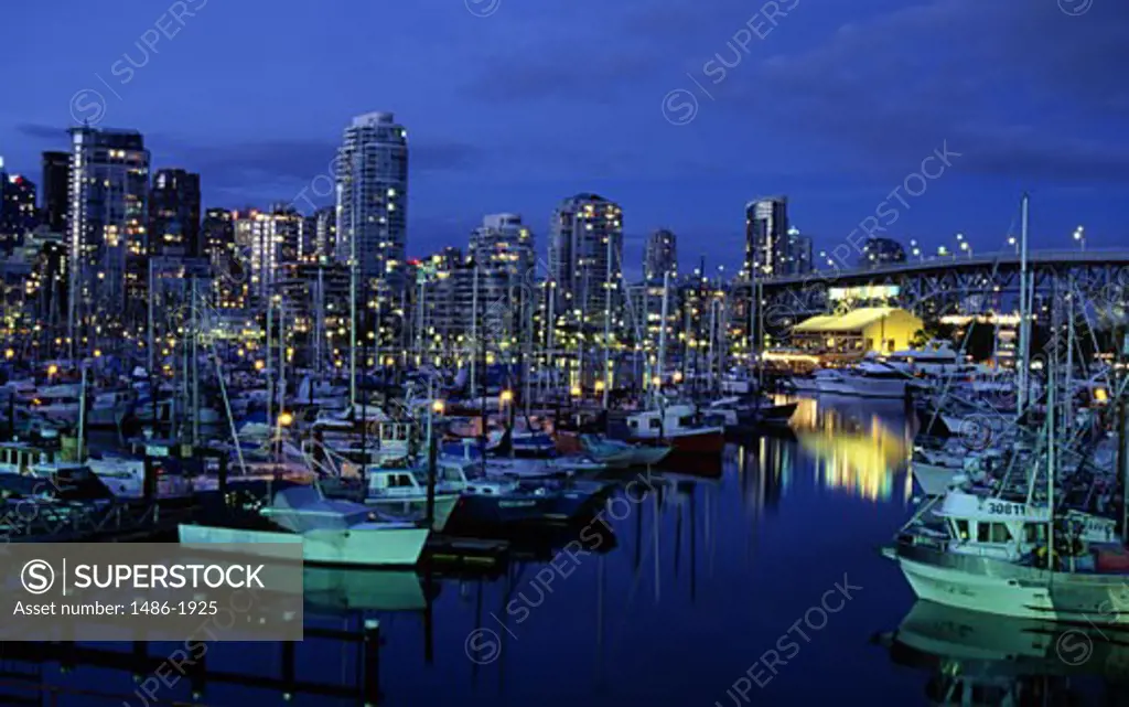 Canada, British Columbia, Vancouver, False Creek, mooredyachts and illuminated buildings on the background