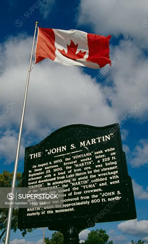 Low angle view of a Canadian flag with an information board, John S. Martin Memorial, Port Huron, Michigan, USA