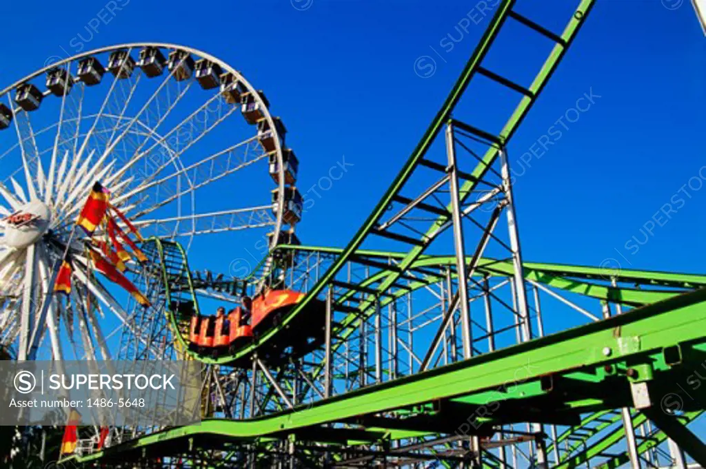 Low angle view of a ferries wheel and a rollercoaster in an amusement park, Orange County Fair, Costa Mesa, California, USA