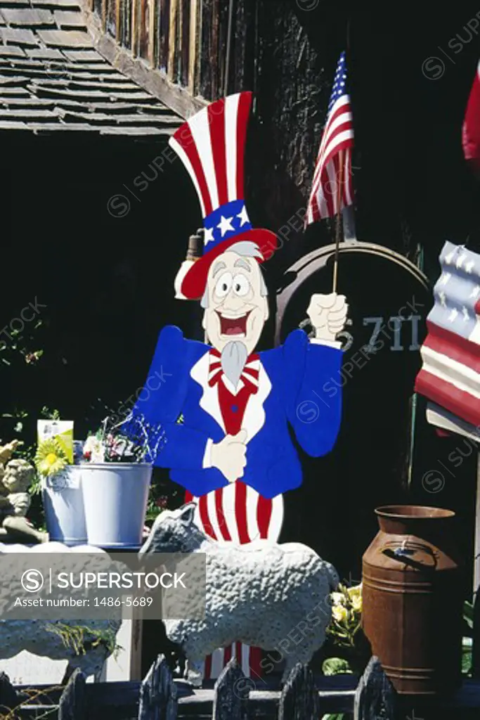 Cartoon character wearing bowler hat painted in American flag colors, holding American flag in theme park