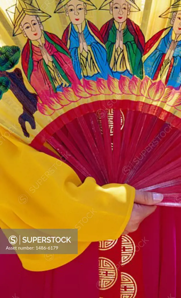 Close-up of a human hand holding a folding fan