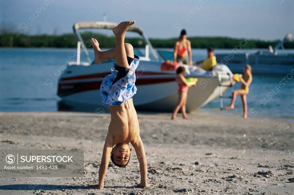 Boy walking on his hands on the beach