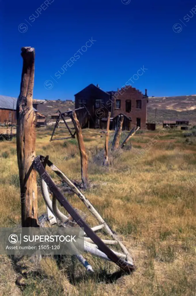 Old wagon wheel lying against a wooden pole in front of a house, Bodie State Historic Park, California, USA
