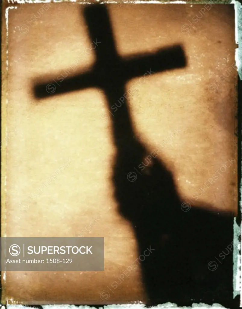 Shadow of a person's hands holding a cross