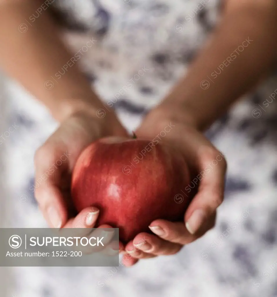 Close-up of human hands holding an apple