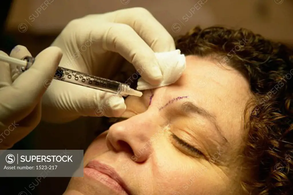Close-up of a woman getting a botox injection on her eyebrows from a surgeon