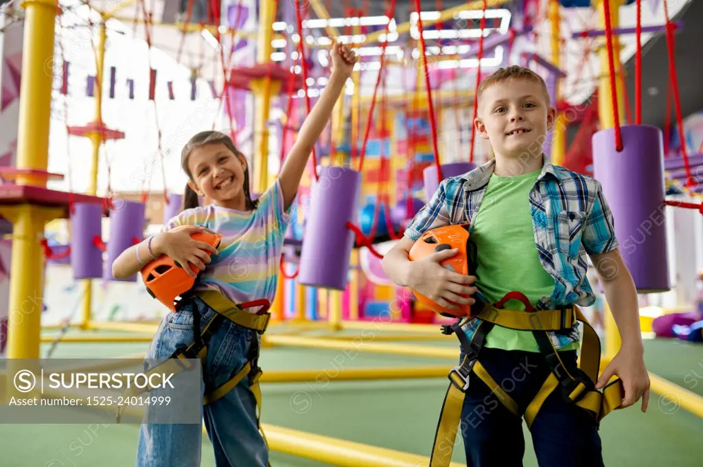 Two children poses in climbing area in entertainment center, young climbers. Boy and girl having fun on ropes, kids spend the weekend on playground, happy childhood. Two children poses in climbing area, young climber
