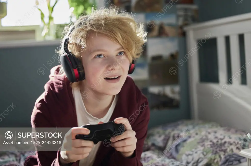 Excited Teeange Girl With Wireless Headphones Gaming Online In Bedroom At Home