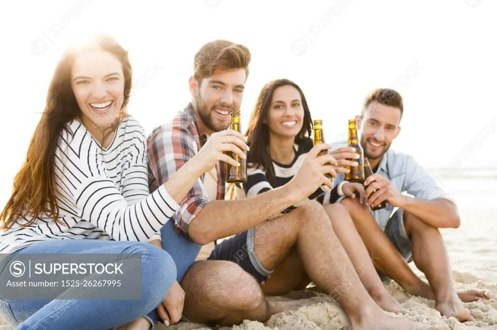 Friends having fun together at the beach and drinking a cold beer