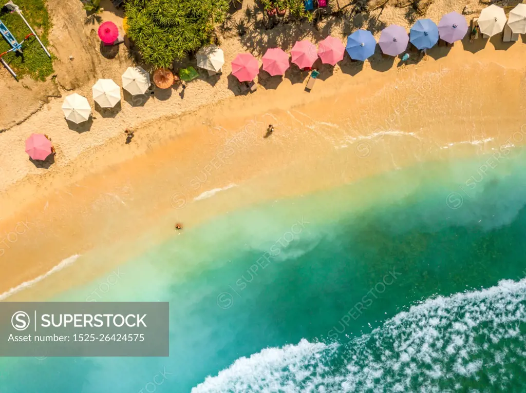 Indonesia. Tropical sandy beach in sunny weather. Turquoise water and beach umbrellas. Aerial view. People on a Tropical Beach. Aerial View