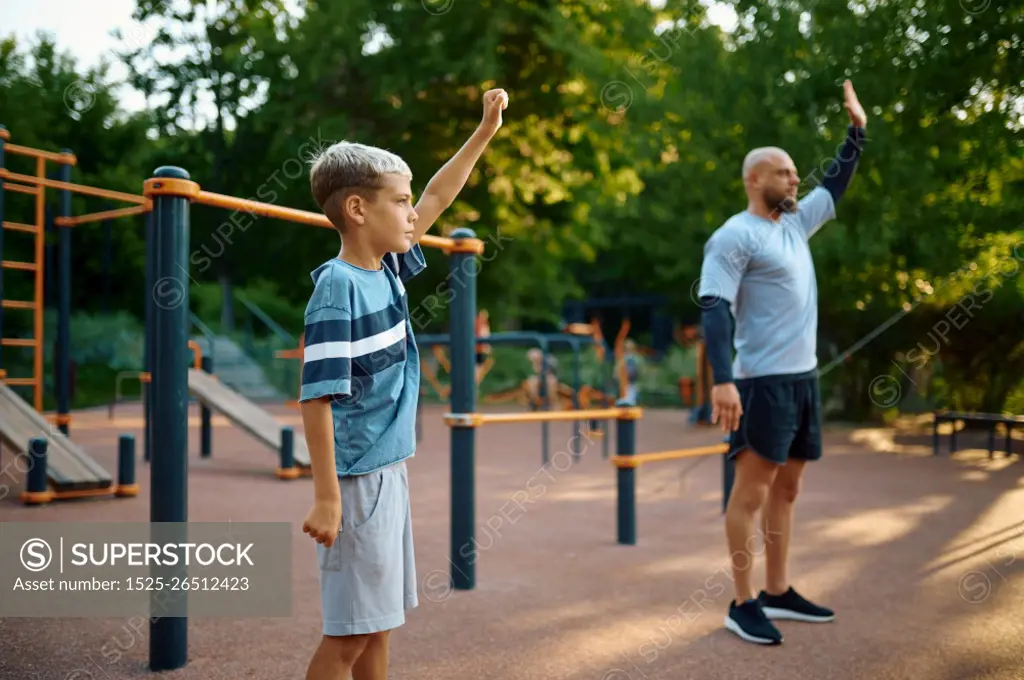 Dad and son, sport training on playground outdoors. The family leads a healthy lifestyle, fitness workout in summer park. Dad and son, sport training on playground