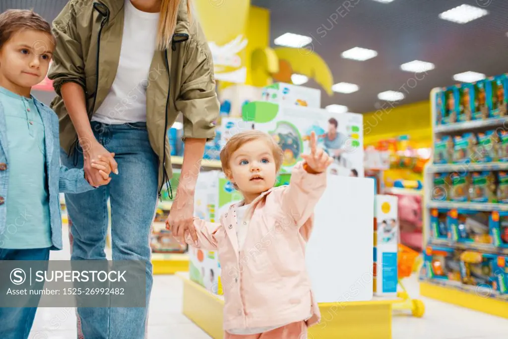Mother with her little children in kids store. Mom with daughter and son together choosing toys in supermarket, family shopping. Mother with her little children in kids store