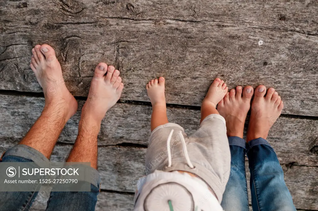 Bare feet of family. Wooden bridge. Mom, dad and baby walk bare feet on the wooden bridge. Happy young family spending time together. The concept of family holiday. copy space. selective focus.. Bare feet of family. Wooden bridge. Mom, dad and baby walk bare feet on the wooden bridge. Happy young family spending time together. The concept of family holiday. copy space. selective focus