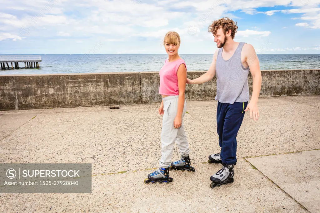 Friendship and spending time together. Outdoors activities sport and free time. Summertime exercising.. Young couple have fun together rollerblading in park learning.. Friends learn rollerblading together have fun at park.