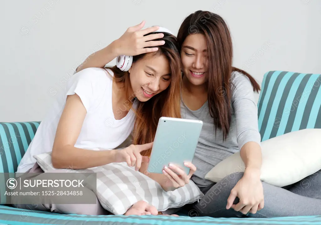 LGBT, Young cute asian lesbian couple wearing headphone and using tablet with happy moment, homosexual, lesbian couple lifestyle