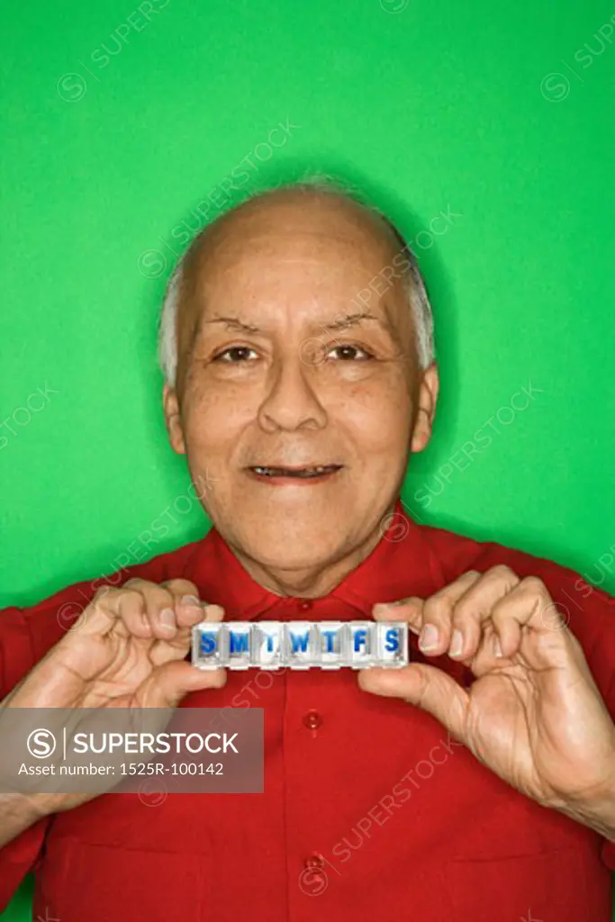 Mature adult Caucasian male holding pill organizer.