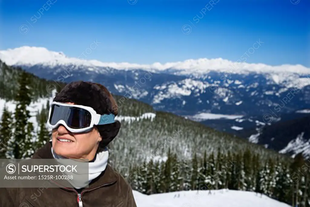 Caucasian middle-aged woman skier in goggles posing on mountain.