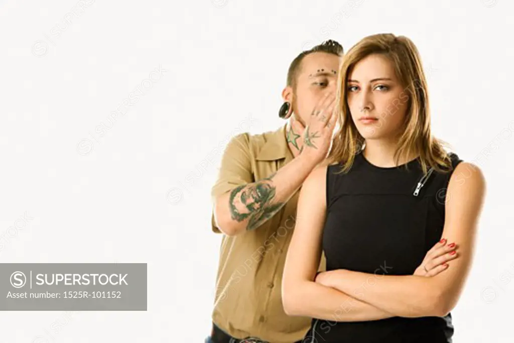 Caucasian mid-adult man whispering into ear of teen female.
