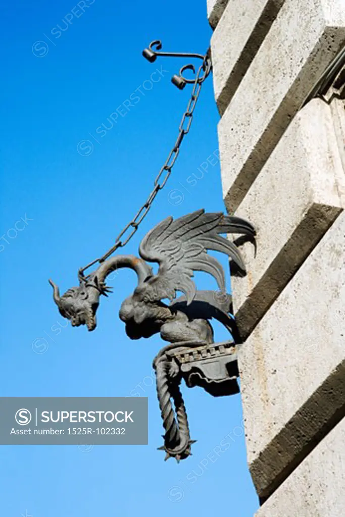 Winged gargoyle chained to wall.