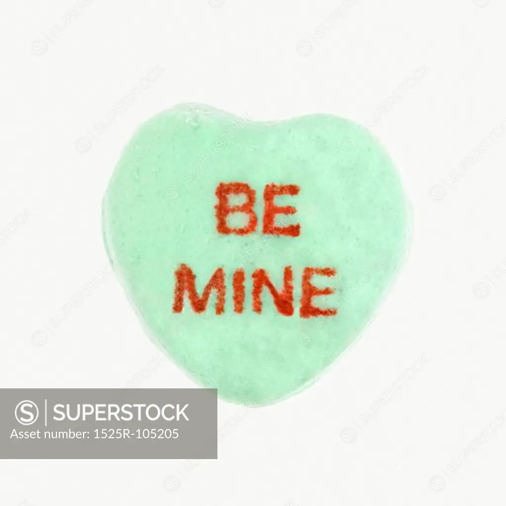 Green candy heart that reads be mine against white background.