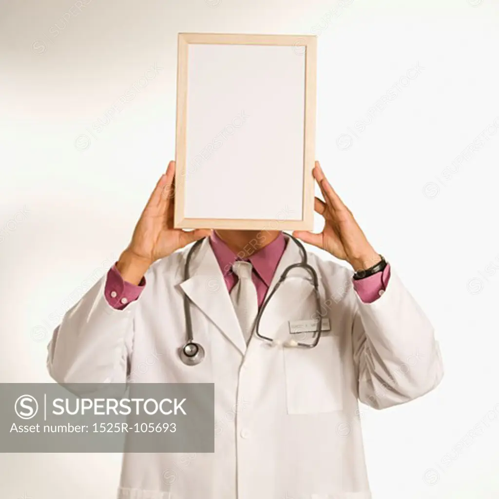 Asian American male doctor holding blank sign over face.