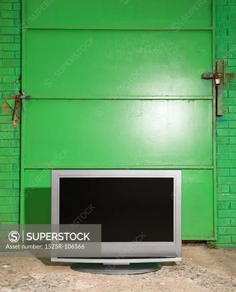 Flat panel television in front of green metal door.