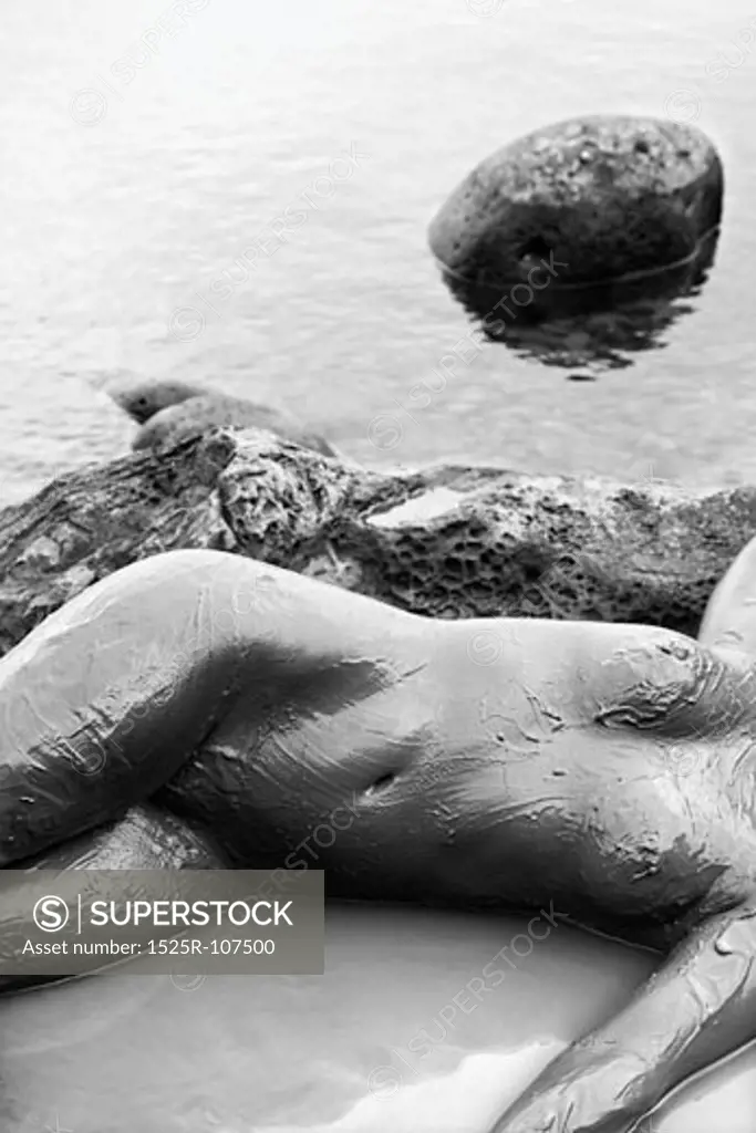 Young adult Caucasian female nude lying on rocky coast of Maui, Hawaii.
