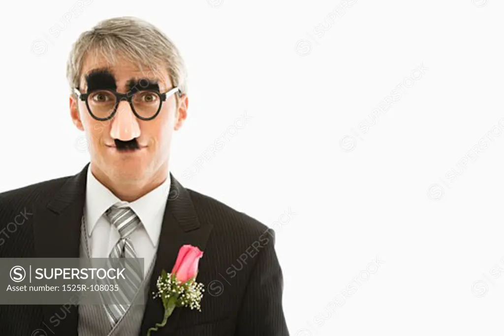 Caucasian groom wearing groucho glasses making eye contact.