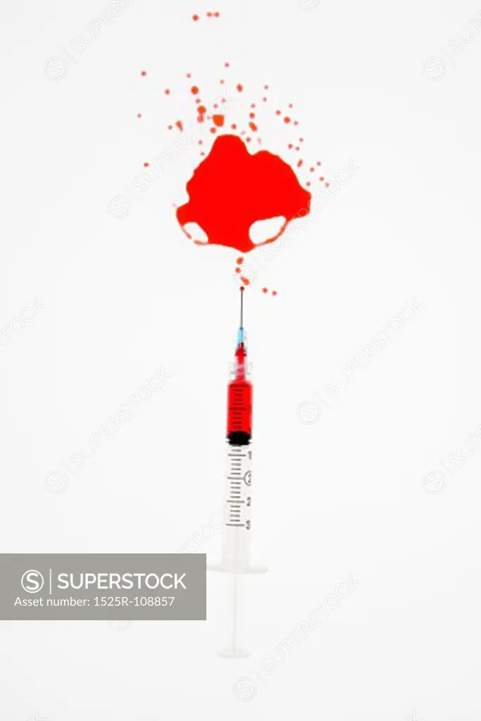 Hypodermic needle  with red liquid sprayed on white background.