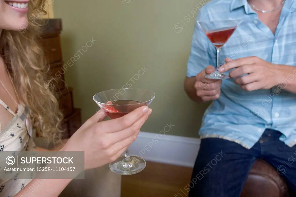 Mid section view of a young couple holding martini glasses