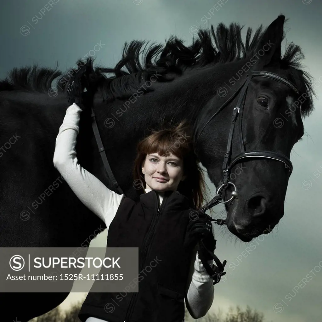 Beautiful young woman with a black horse