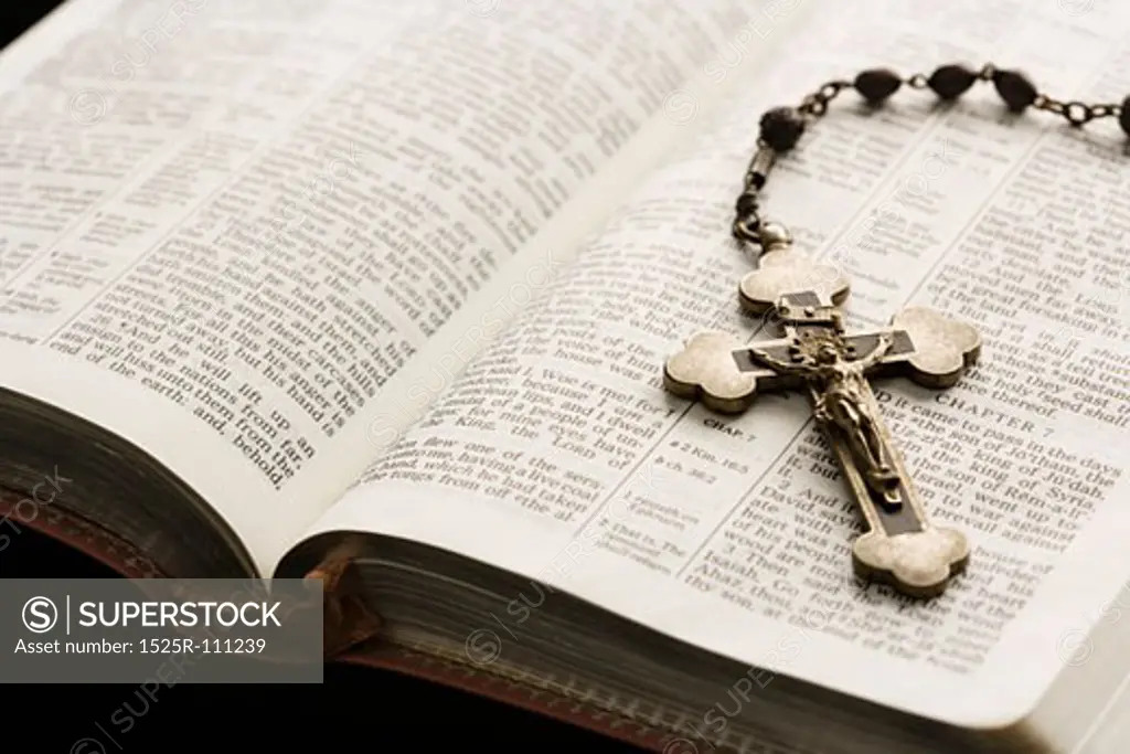 Rosary with crucifix lying on open Bible.