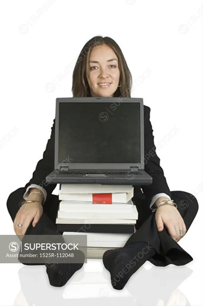 business woman sitting on the floor behind a laptop and some books