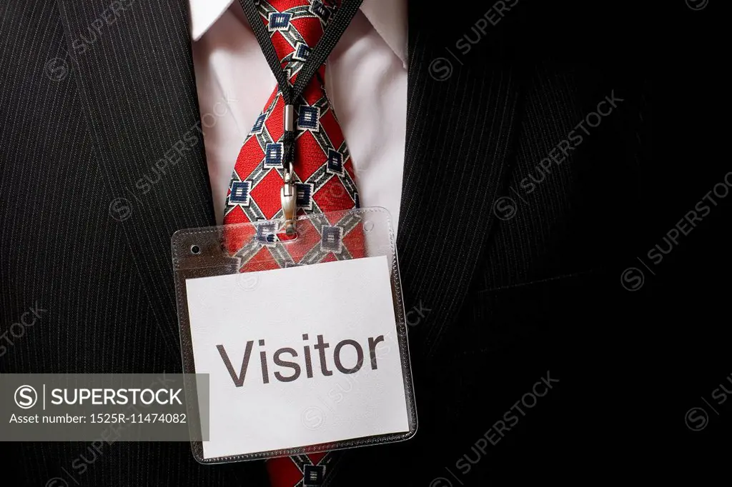 businessman wearing a visitor identification badge around his neck