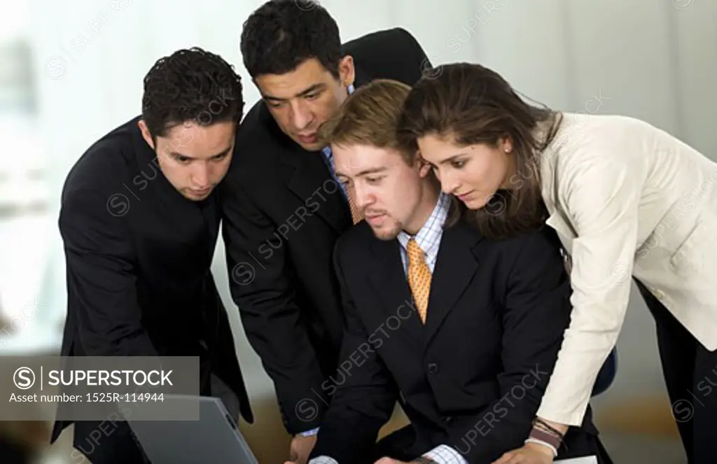 Business team in an office environment all wokring on a laptop computer