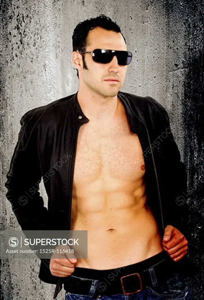 fashion male portrait isolated wearing sunglasses over a dark concrete background