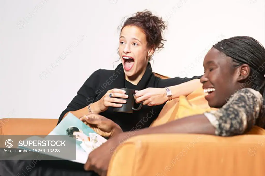 Two young women sitting on a couch laughing