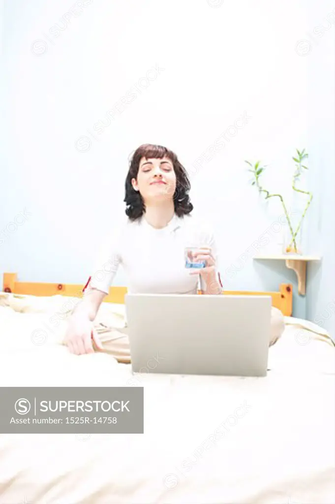 Young woman sitting in bed with a laptop in front of her