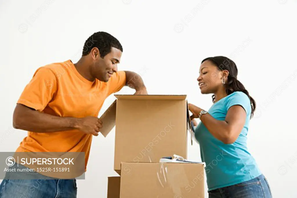 African American male and female couple packing cardboard boxes.