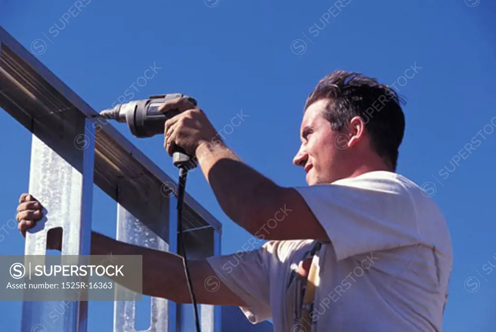 A worker drilling into a scaffolding