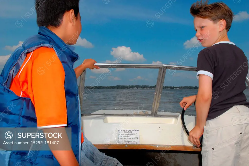 Two boys steering small speedboat