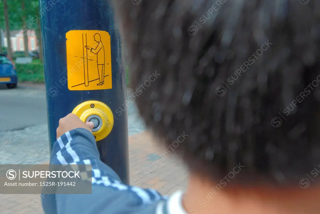 Child pushing road crossing button