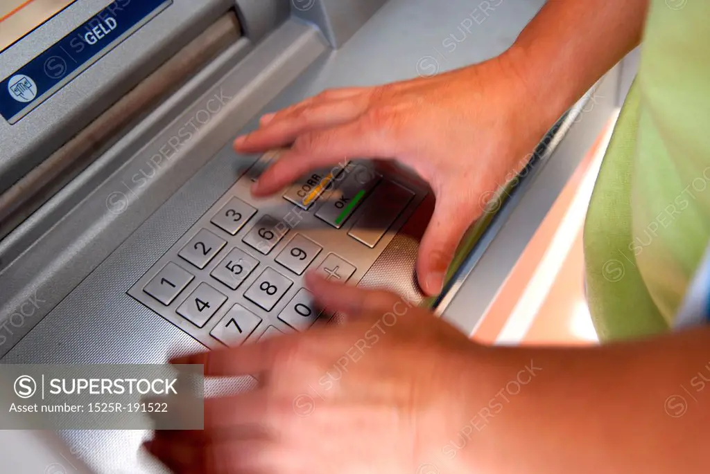 Woman inputting pin into atm machine