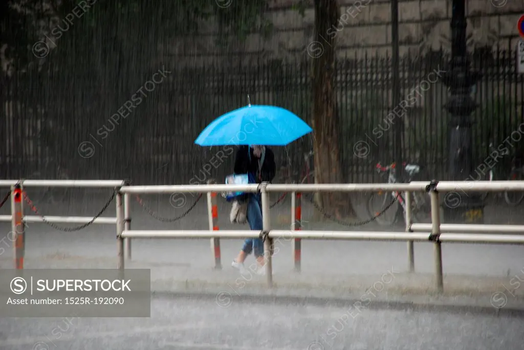 woman with blue umbrella braving heavy rain